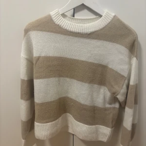 Randig stickad tröja från H&M - Säljer en mysig stickad tröja från H&M i beige och vit med breda ränder. Tröjan har en rund halsringning och långa ärmar, perfekt för kyligare dagar. Passar bra till både jeans och kjol. 🧶i väldigt bra skick, pris kan diskuteras. Passar även för xs.