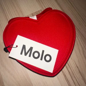 Söt hjärtformad väska - Helt ny, oanvänd väska från molo. Säljes på grund av att jag aldrig använt den. Får plats med det nödvändigaste. 