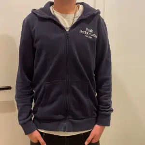 Säljer denna snyggmörkblå zip-hoodie från Peak performance. Tröjan har en broderad logga på bröstet och perfekt nu till vintern. Tröjan är använd en del men fortfarande perfekt skick. Riktigt skön och lätt att stila. Storlek 160cm = xxs vuxenstorlek.