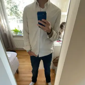 Säljer en stilren creme vit/beige långärmad skjorta. Perfekt för både vardag och fest. Skjortan har en klassisk krage och knappar framtill. Den är i normal passform och passar bra till jeans eller kostymbyxor. Jag har använd denna som overshirt