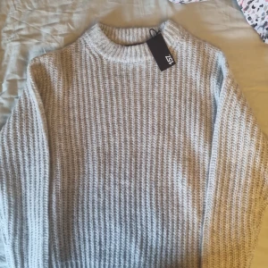 Grå stickad tröja - Säljer en supermysig grå stickad tröja i storlek XS. Perfekt för kyliga dagar med sin varma och mjuka textur. Tröjan har en klassisk design med långa ärmar och en rund halsringning. Ny med tagg kvar! tycker den sitter konstigt på mig. Kontakta gärna💕