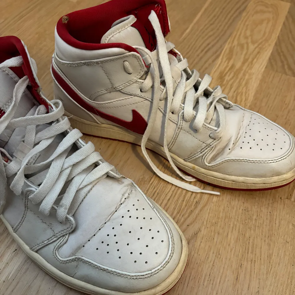 Säljer ett par klassiska Nike Air Jordans i vitt med röda detaljer. Skorna har en hög modell med snörning och den ikoniska Air Jordan-loggan på sidan. De är i välanvänt skick men fortfarande riktigt snygga och bekväma. Perfekta för både vardag och fest!. Skor.