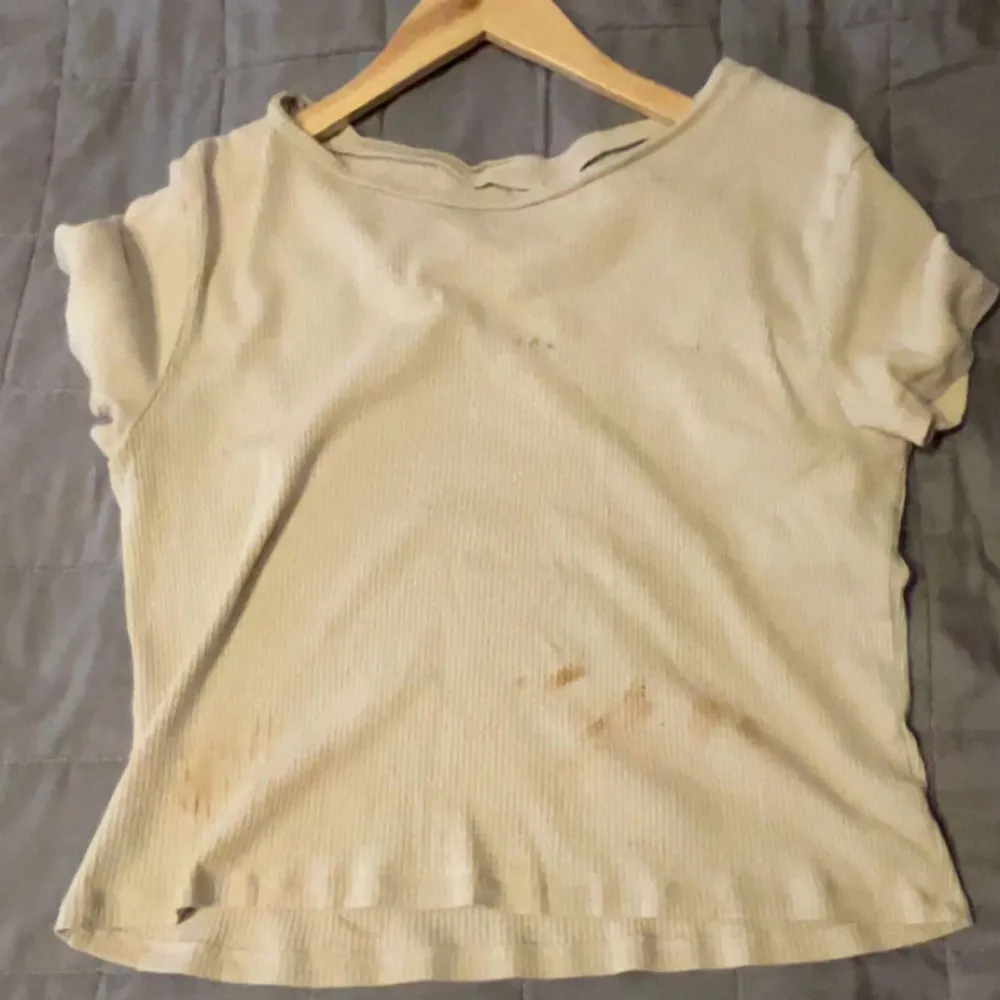 Säljer en beige ribbad t-shirt i välanvänt skick. Den har korta ärmar och en enkel design. Perfekt för en avslappnad look eller som basplagg i garderoben. Fläcken går även att tvätta bort . T-shirts.