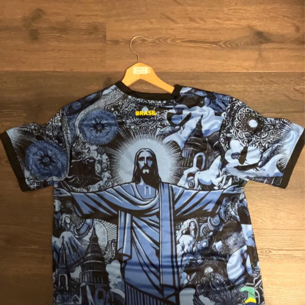 Säljer en unik fotbollströja från Nike i blått och svart med ett coolt Kristusmotiv och detaljer av brasilianska symboler. Tröjan har korta ärmar och är perfekt för både match och vardag. Den är i nyskick och redo för en ny ägare!. T-shirts.