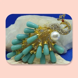 Brosch/Hänge - Påfågel i turkos - Den här läckra broschen i form av en påfågel har guldfärgad metall, transparenta kristaller och större pärlor i turkos, måtten är ca 8 × 5 cm. Finns även en ögla på broschens baksida så denna kan användas som hänge till halsband. 