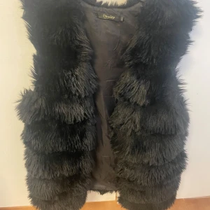 Svart pälsväst från Reality - Säljer en snygg svart pälsväst från Reality i storlek M. Västen är perfekt för att ge din outfit en extra touch och passar bra till både vardag och fest. Den är i mycket bra skick och supermjuk!