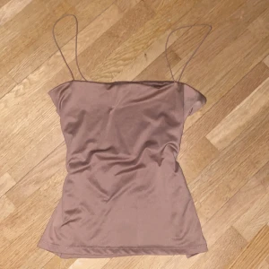 Beige linnetopp från Amisu - Säljer en stilren beige linnetopp från Amisu i storlek S. Toppen har tunna axelband och är perfekt för sommardagar. Materialet känns mjukt och skönt mot huden. Passar både till vardags och festliga tillfällen. 🌟