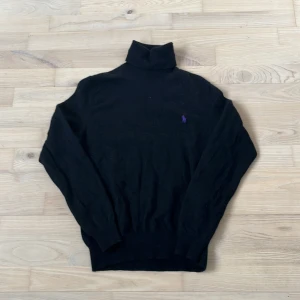 Svart polotröja från Polo Ralph Lauren - Säljer en stilren svart polotröja från Polo Ralph Lauren i merinoull. Tröjan har en broderad lila logga på bröstet och är perfekt för både höst och vinter. Den är i mycket bra skick och supermjuk att ha på sig. Passar perfekt för en elegant och varm look! Obs! Sitter som en S i storlek 
