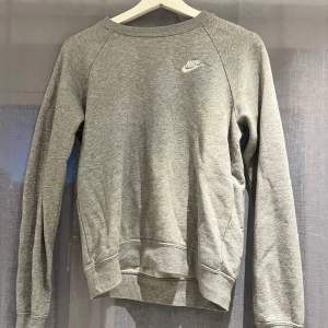 Säljer en grå sweatshirt från Nike i mycket bra skick. Den har en klassisk design med rund hals och långa ärmar. Perfekt för både vardag och träning. Nike-loggan är broderad i vitt på bröstet. Superbekväm och stilren! Använd gärna köp nu 💕