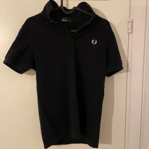 Svart kortärmad pikétröja från Fred Perry - Säljer en stilren svart pikétröja från Fred Perry i storlek S. Tröjan har en klassisk design med korta ärmar och en liten broderad logga på bröstet. Perfekt för både vardag och fest! 🖤