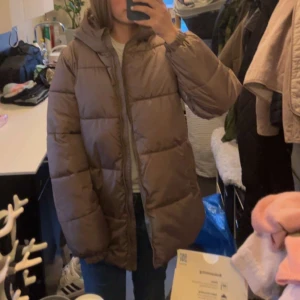 Brun pufferjacka med huva - Säljer en mysig brun pufferjacka med huva. Perfekt för kyliga dagar! Jackan har en dragkedja framtill och långa ärmar. Den är i bra skick och passar perfekt för höst och vinter. Storleken är normal och den är superbekväm att ha på sig. Den är nyköpt så bara andvänd en gång!