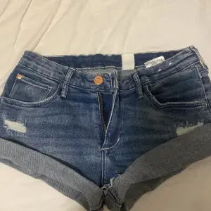 Säljer ett par snygga blå jeansshorts från H&M i storlek 152.  slitna detaljer och uppvikta ben. Perfekta för sommardagar. Dragkedja och knapp framtill för enkel stängning. Passar perfekt till en t-shirt eller linne!Skriv vid fler bilder eller fundering💘 Lite större i storlek💘 Priset kan diskuteras 