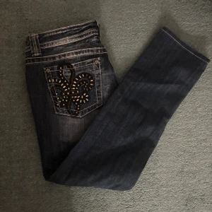 Mörkblå jeans från Miss Me - Snygga mörkblå jeans från Miss Me i storlek 31. De har en cool broderad detalj med pärlor på bakfickan som verkligen sticker ut. Perfekta för både vardag och fest! 🖤obs! andvånda ute max 3 ggr❤️