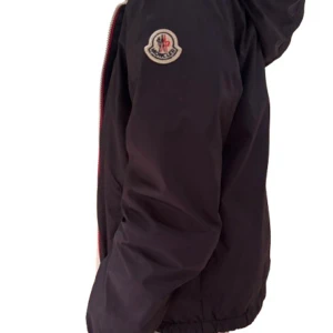 Mörkblå  jacka från Moncler - Säljer en snygg svart jacka från Moncler i mycket bra skick. Den har en dragkedja framtill och Moncler-loggan på ärmen. Perfekt för höst och vår med sin stilrena design och bekväma passform. Passar någon som är 152 cm lång.