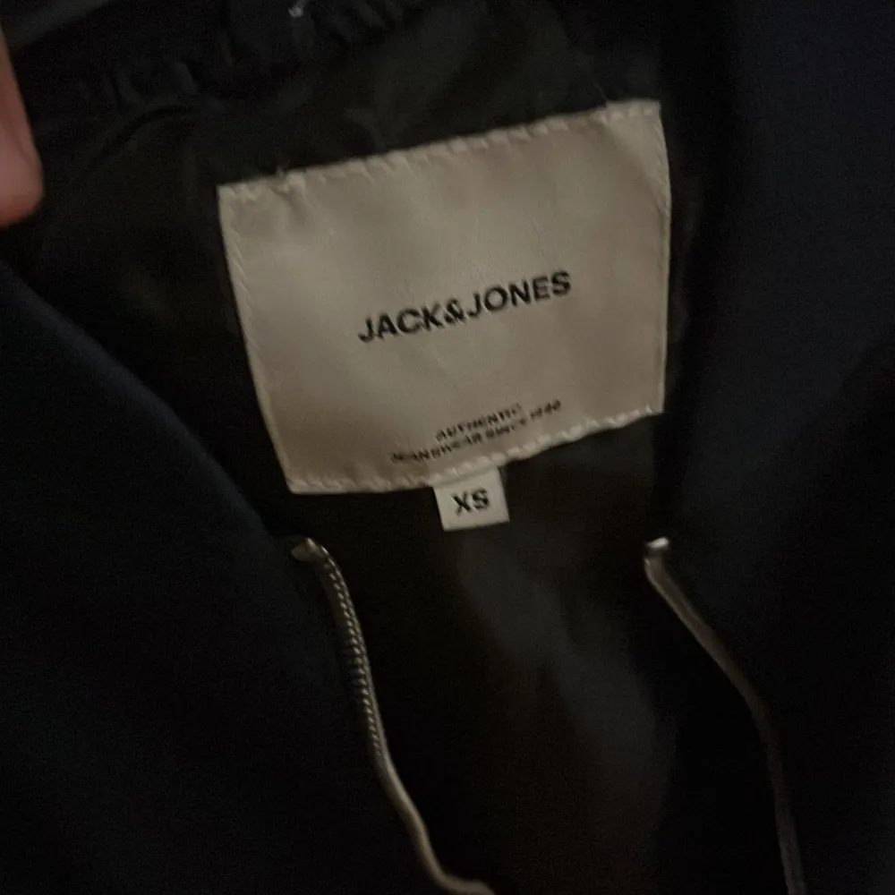 Säljer en mörkblå bomberjacka från Jack & Jones i storlek XS. Jackan har en dragkedja framtill och två fickor med dragkedjor. Perfekt för höst och till vinter.. Takit.