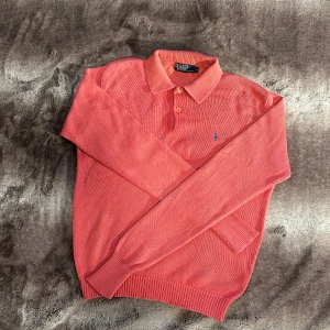 Polo Ralph Lauren - Säljer en snygg röd pikétröja från Polo Ralph Lauren. Tröjan har långa ärmar och en klassisk krage med knappar. Perfekt för en stilren look.