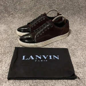 Svarta sneakers från Lanvin - Snygga svarta sneakers från Lanvin med glansig tå och snörning. Skorna har en vit sula och kommer med en svart förvaringspåse med Lanvin-logga.