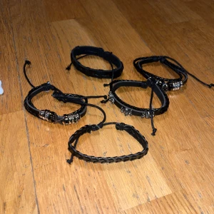 Svarta läderarmband med metallringar - Säljer ett set av svarta läderarmband med justerbara band och dekorativa metallringar. Perfekt för en stilren och edgy look. Passar både till vardag och speciella tillfällen.