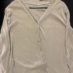 Ljus grön ribbad blus - Snygg ljus grön blus med ribbad textur och v-ringning. Blusen har långa ärmar och knappar framtill, vilket ger en stilren look. Perfekt för en elegant och avslappnad stil.