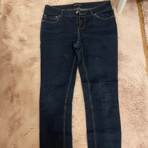 Mörkblå jeans från ONLY - Snygga mörkblå jeans från ONLY med klassisk femficksdesign och kontrastsömmar. Perfekta för en avslappnad stil. De har en knapp och dragkedja framtill.