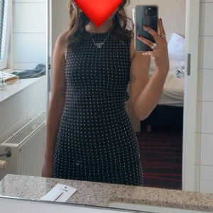 Svart klänning med glittriga detaljer från Zara - Snygg svart klänning från Zara med glittriga rhinestones över hela tyget. Klänningen är ärmlös och har en tight passform som framhäver figuren. Perfekt för en kväll ute eller en speciell tillställning. Använd en gång 