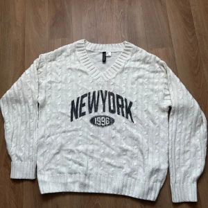Vit stickad tröja från H&M Divided - En vit, kabelstickad tröja med tryck och v-ringning från H&M Divided. Använd några gånger så kan finnas få tecken på användning, men inget som framstår! 🤍