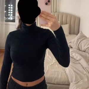 Svart långärmad tröja med hög nacke  - Säljer en stilren svart hög nacke med lång ärm tröja. Perfekt för kyligare dagar och lätt att matcha med olika outfits. Tröjan har en tight passform som framhäver figuren.