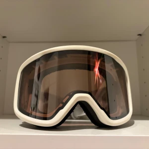 Skidglasögon  - Snygga vita skidglasögon från Cross Sportwear med bred elastisk rem. Glasögonen har en mörk tonad lins som ger bra skydd mot solen. Perfekta för vintersport och äventyr i snön.