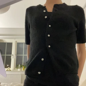 Svart kofta med knappar - Snygg svart kofta med korta ärmar och dekorativa knappar. Jätte skönt material. Använd ändast 2 gånger.