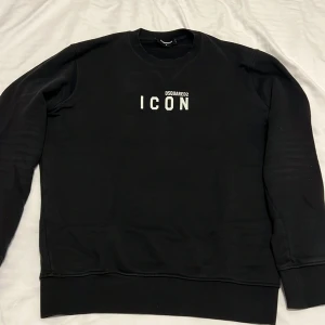 Svart sweatshirt från Dsquared2 - Snygg svart sweatshirt från Dsquared2 med texten 'ICON' tryckt på framsidan. Tröjan har en klassisk rund hals och långa ärmar. Perfekt för en stilren och avslappnad look.