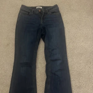 Mörkblå bootcut jeans - Snygga mörkblå bootcut jeans med klassisk femficksdesign. Perfekta för en avslappnad stil. De har en knapp och dragkedja framtill.