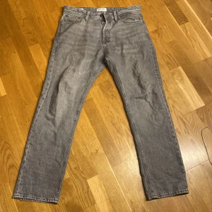 Grå jeans från Jack & Jones - Säljer ett par grå jeans från Jack & Jones i modellen Relaxed/Chris. De har en avslappnad passform och klassisk design med fem fickor och knappgylf.
