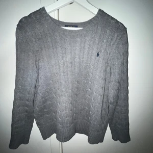 Grå kabelstickad tröja från Ralph Lauren - Säljer en stilren grå kabelstickad tröja från Ralph Lauren med kabelstickat mönster. Tröjan har en klassisk rund hals och långa ärmar. Perfekt för kyligare dagar. Säljer då den är för liten. Tröjans skick är ca 9/10. Nypriset är 2000kr och jag säljer för 649kr vilket är ett riktigt bra pris om du frågar mig😊 fråga gärna frågor om hur lång du bör vara för den ska passa osv🙌