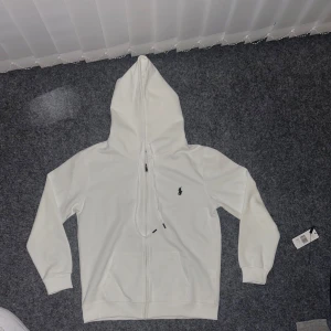 Vit hoodie från Polo Ralph Lauren - KAN GÅ NER I PRIS FÖR SNABB AFFÄR! Säljer denna stilrena och högkvalitativa ralph lauren zip up. Den är HELT NY OCH OANVÄND. MVH Elt.Wear