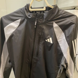 vindjacka från Adidas - Vindjacka från adidas. Storlek M passar S. både tjej o kille. Köptes för ca 600 på stadium. 