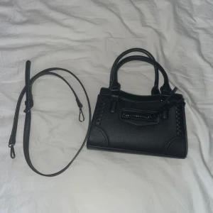 Svart handväska med avtagbar axelrem - Snygg svart handväska i med avtagbar axelrem. Väskan är är mycket bra skick och är perfekt för en stilren look. Klicka gärna på köp nu💕