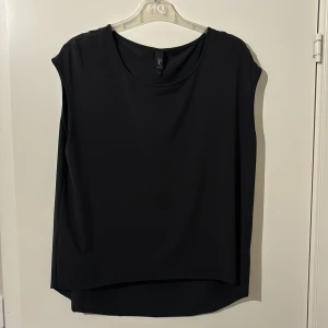 Svart ärmlös topp från Zoul - Snygg svart ärmlös topp från Zoul. Perfekt för en stilren look med rund halsringning och mjukt material. Passar bra till både jeans och kjol.