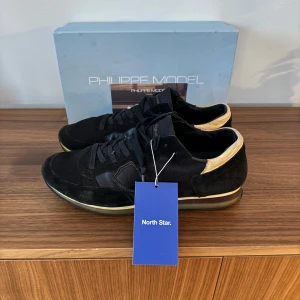 Phillipe Model Trainers - Snygga svarta sneakers från Philippe Model med detaljer i beige. Skorna är i ett riktigt bra skick och box, kort och skorna följer med! Bara höra av dig vid minsta lilla fundering🔥🤗