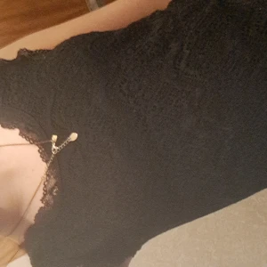 Svart spetstopp - Elegant svart spetstopp med spetsdetaljer och ärmlös design. Perfekt för en stilren look.