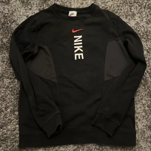 Svart långärmad tröja från Nike - Säljer en svart långärmad tröja från Nike med röd och vit logga på framsidan.