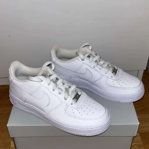 Vita Nike Air Force sneakers - Säljer ett par klassiska vita Nike Air Force sneakers. Skorna har en stilren design med snörning och den ikoniska Nike-loggan på sidan. Perfekta för en casual look.