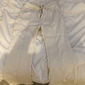 Beige byxor med dragkedja - Snygga beige byxor med dragkedja och knappar. 