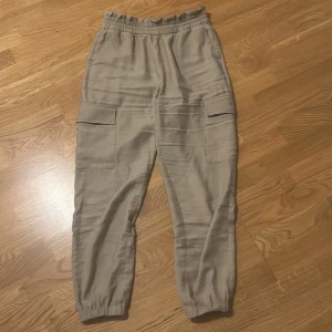 Beige cargopants från Only - Snygga beige cargopants från Only med elastisk midja och muddar vid bensluten. Byxorna har praktiska fickor på sidorna och är perfekta för en avslappnad stil.