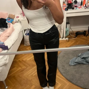Svarta skinnbyxor - Snygga svarta skinnbyxor med hög midja och raka ben. Perfekta för en trendig look. Byxorna har fickor både fram och bak samt bälteshällor.