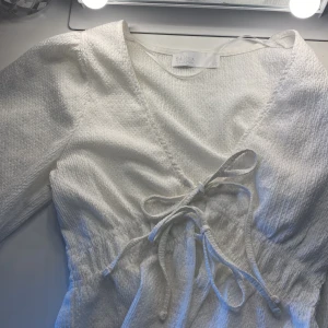 Vit blus/ omlottopp från SAMSA Collection - Säljer en stilren vit omlottopp från SAMSA Collection. Toppen har långa ärmar med 2 knytband. Köpt på Ullared för ca 1 år sedan, men endast använt 1 gång. Inga tecken på användning. Storlek XS. Priset kan diskuteras🤍🤍