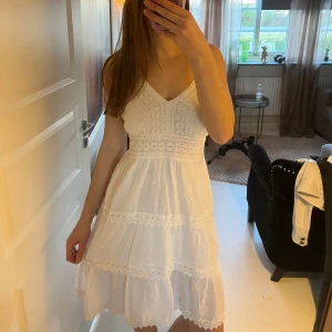 Vit klänning med spetsdetaljer - Charmig vit klänning med spetsdetaljer och smala axelband. Köpt i Spanien så vet ej märke 