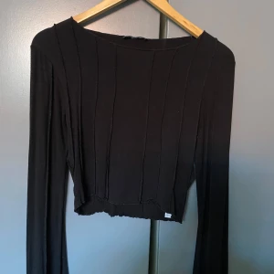 Svart ribbad tröja - En supermjuk tröja med långa, lite vida ärmar och sträck som ger en cool touch!❤️använt några gånger men i fint skick💕 lite croppad i modellen. Storlek M men skulle säga at den är lite liten i storleken så passar S till M beroende på vilken passform man gillar!