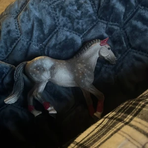 Grå hästfigur med röda detaljer - Säljer en detaljerad grå hästfigur med röda öron och benband. Perfekt för samlare eller som dekoration. Hästen har en realistisk design med fina detaljer på kroppen. En av mina första hästar😀😀