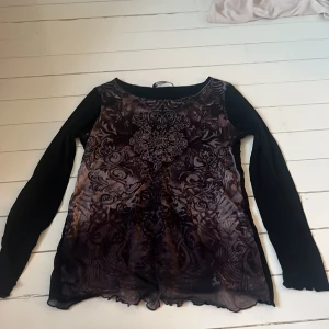 Mönstrad långärmad topp från Betty Barclay - Snygg långärmad topp från Betty Barclay med ett detaljerat mönster i svart och lila. Toppen har en elegant design med spetsdetaljer vid fållen och är perfekt för en stilfull look. På framsidan sitter trycket i ett löst lager så det är en tre lagrig tröja.💞💞