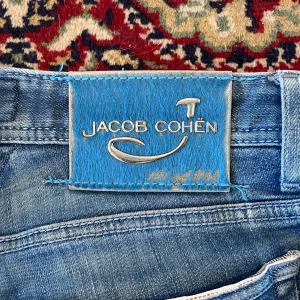 JACOB COHËN Limited edition jeans. - Snygga blå jeans från Jacob Cohën med knappgylf och klassisk femficksdesign. Jeansen har en ljus tvätt och är tillverkade i högkvalitativt denim. Perfekta för en stilren look.